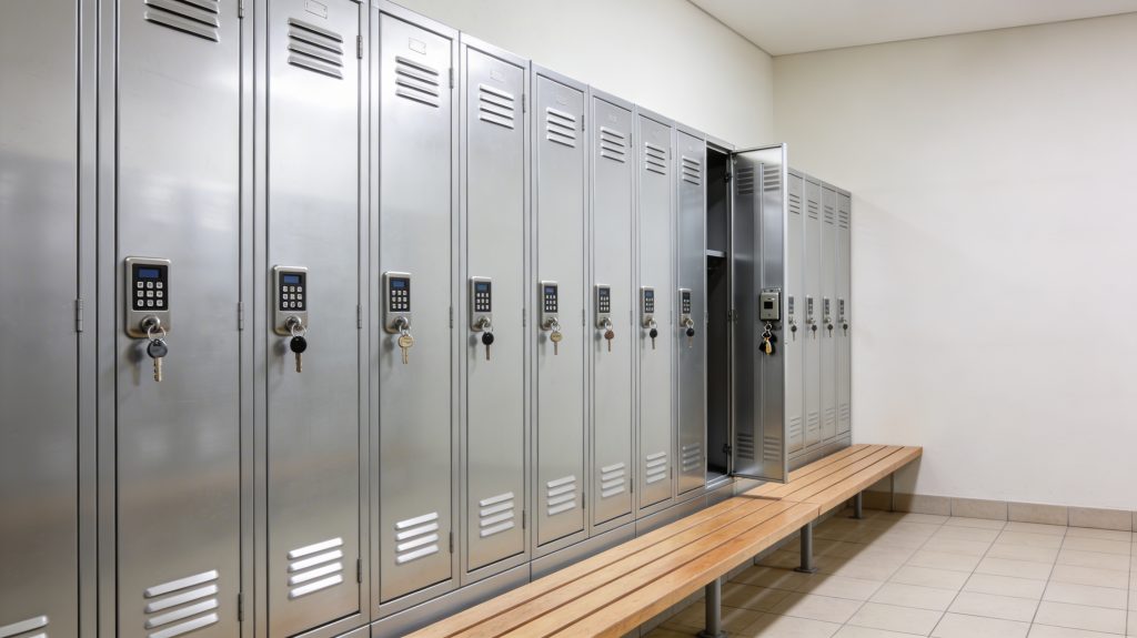Tidy gym locker room with a bench and modern metal lockers fitted with key and code locks.