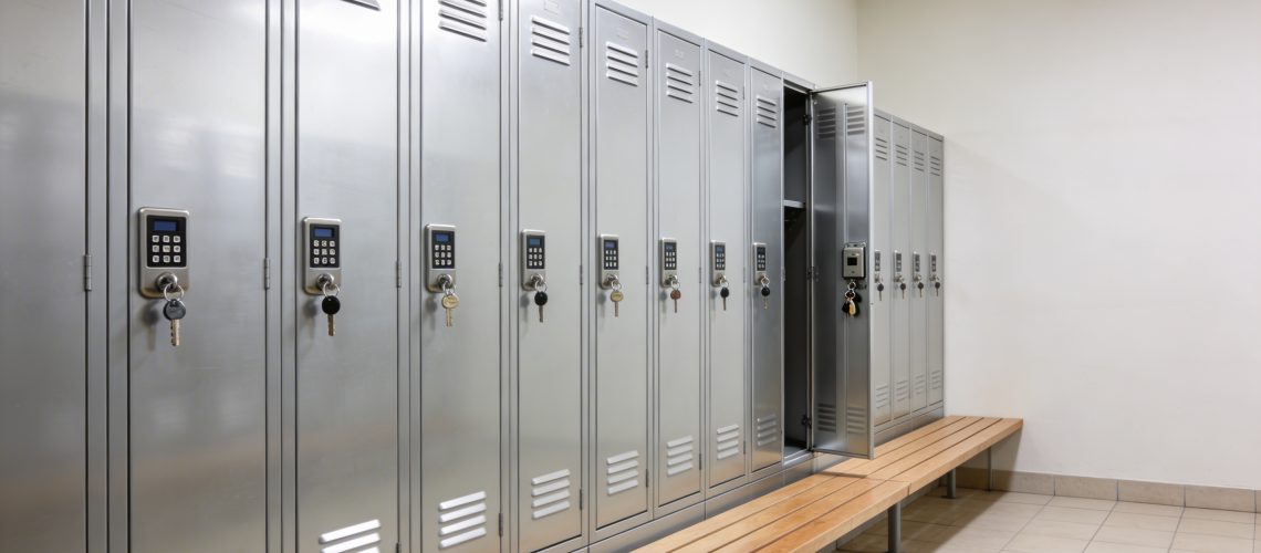 Tidy gym locker room with a bench and modern metal lockers fitted with key and code locks.